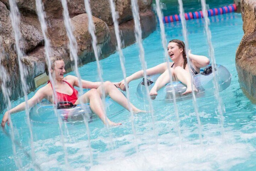 Deux personnes sur des bouées dans une piscine dotée de jeux d’eau. 2
