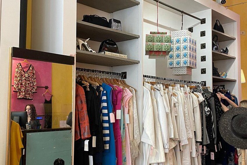 A clothing store with racks of clothes, shelves with shoes, and a mannequin. 1