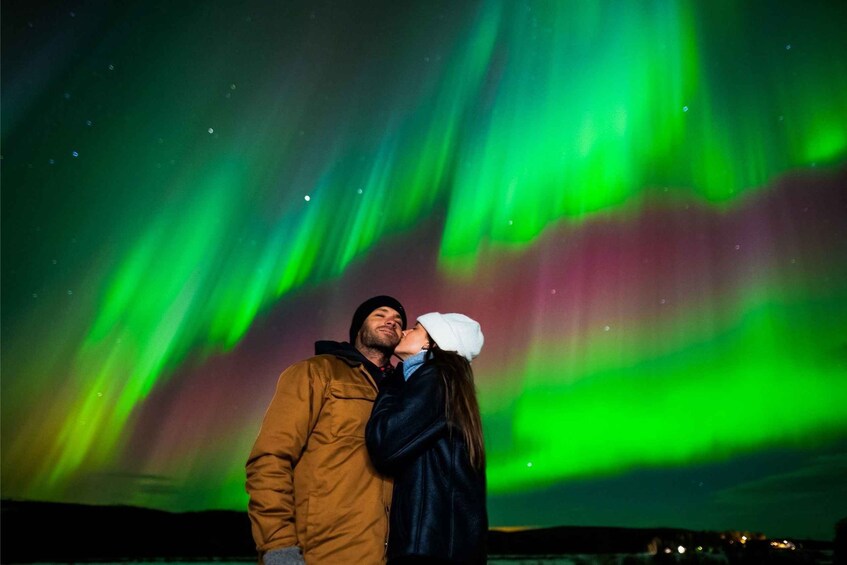 A couple embracing under a night sky with green aurora borealis. 1