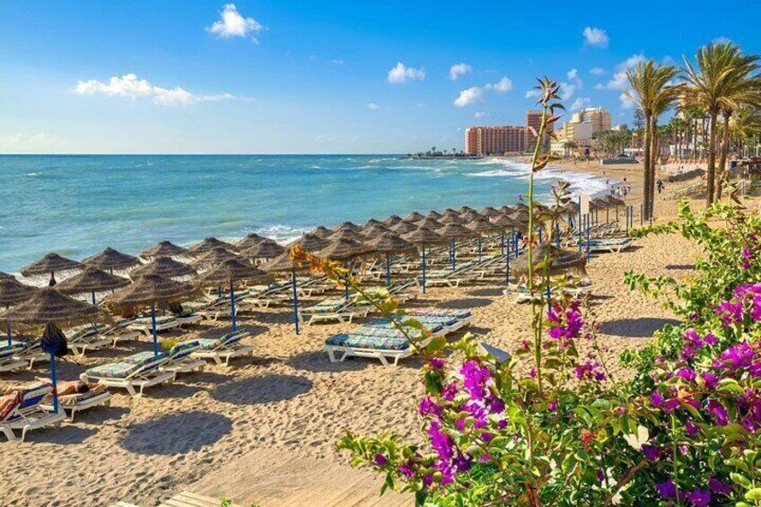 A beach with sun loungers, umbrellas, and a clear blue sky. 3