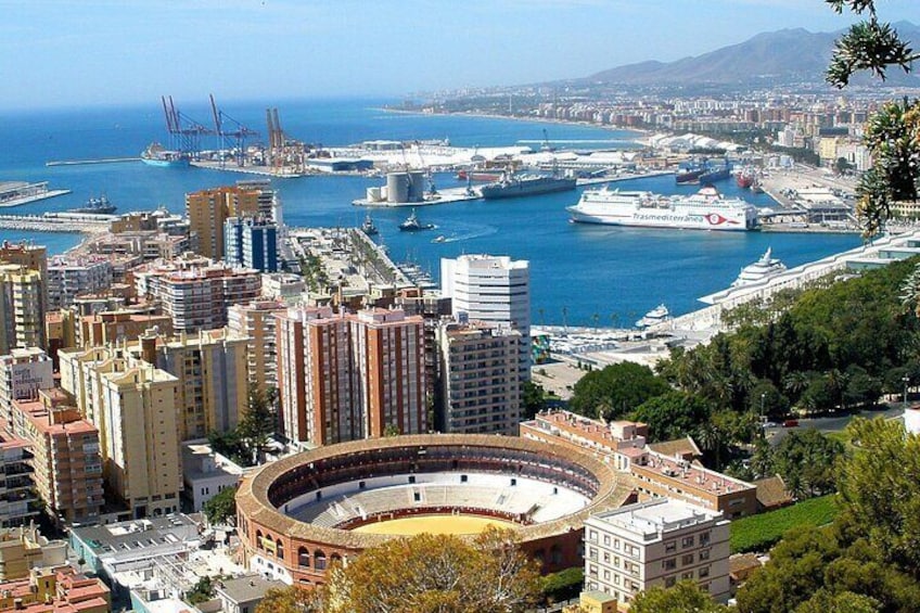 A coastal cityscape with a prominent bullring, port, and modern buildings. 1
