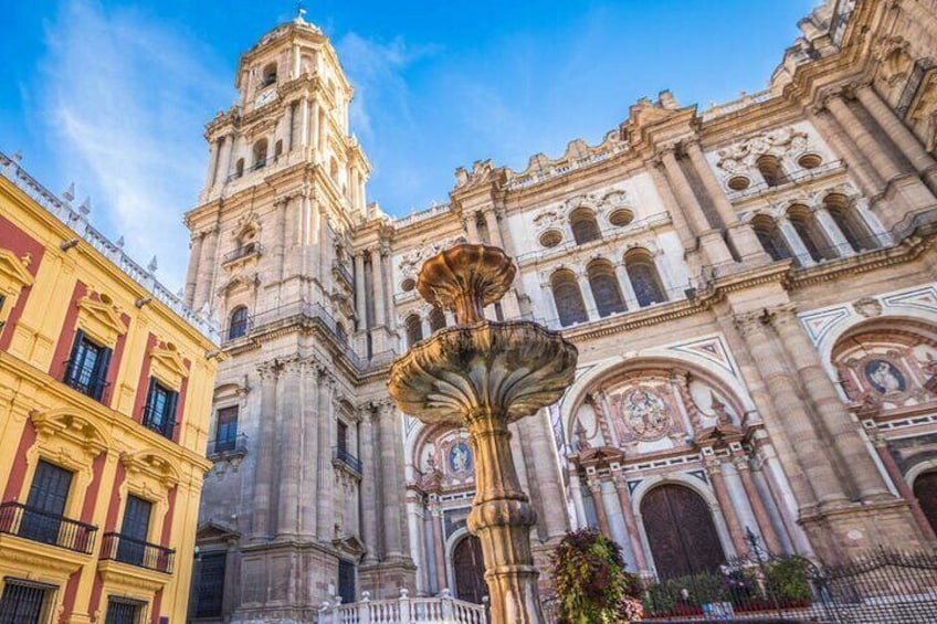 A historic cathedral with a prominent bell tower and a fountain in front. 5