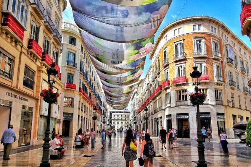 A street lined with buildings and colorful fabric arches. 2