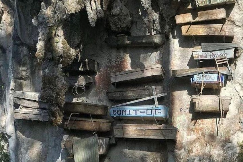Wooden planks and metal containers stacked against a rocky wall. 3
