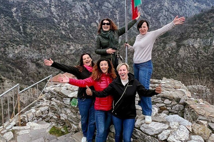 Un groupe de personnes se tient sur un promontoire rocheux, avec une chaîne de montagnes en arrière-plan. 3