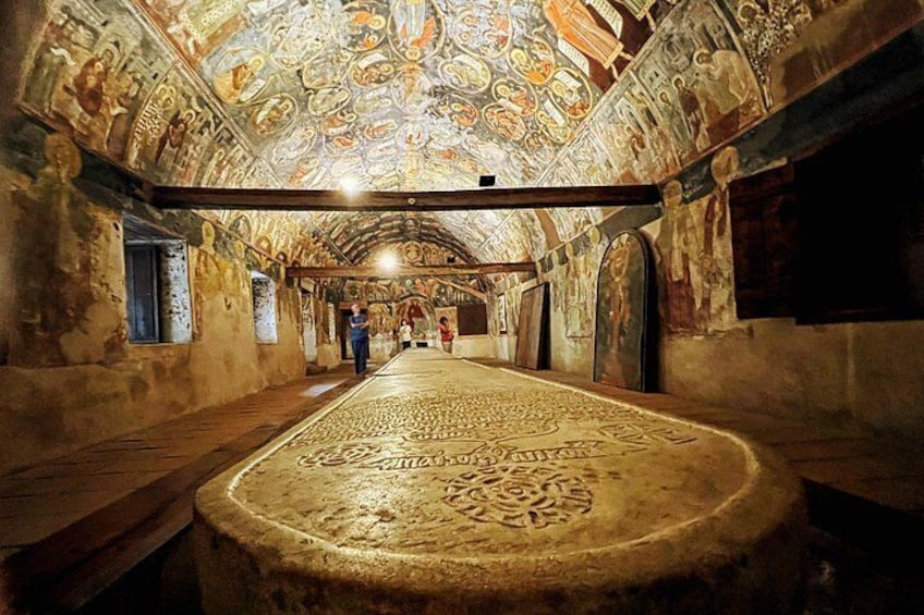 Un intérieur caractérisé par un long tapis décoratif, un plafond élevé orné de fresques détaillées et une série d’arches le long des murs. 4