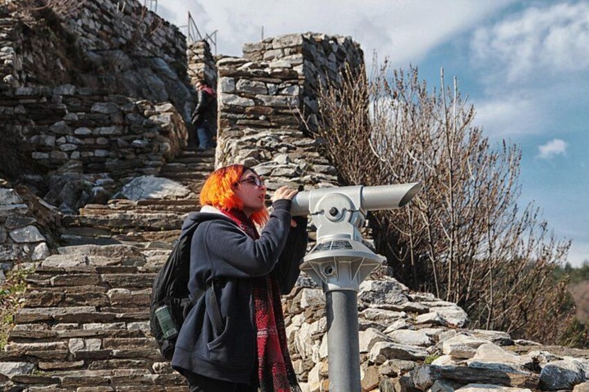 Une personne utilisant un télescope près de ruines en pierre. 2