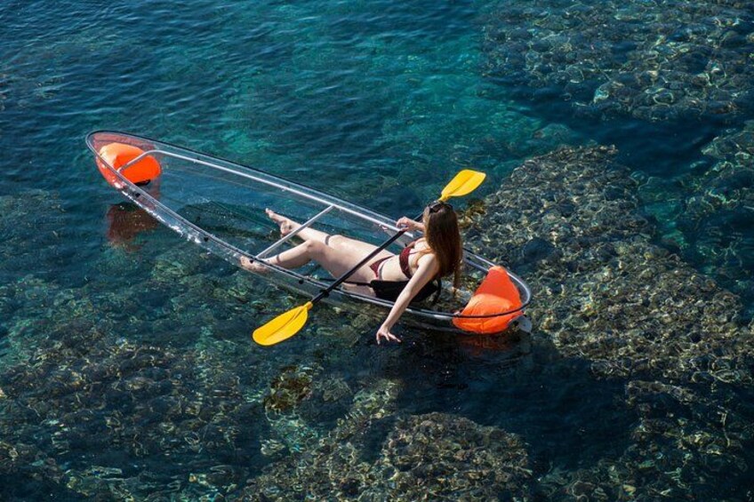 A person kayaking on clear water with visible rocks beneath. 1