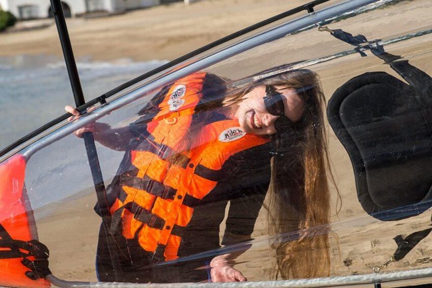 A person in a life jacket leaning out of a vehicle near a beach. 2