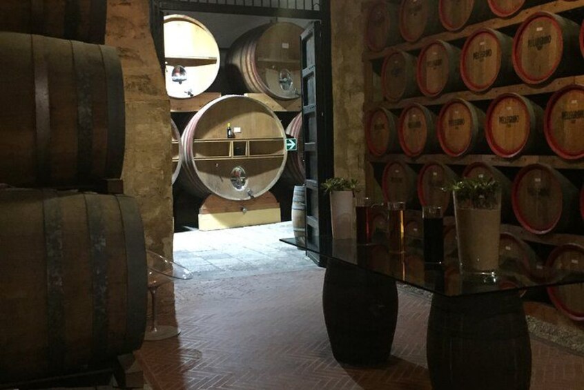 A wine cellar with wooden barrels and a glass display case. 5