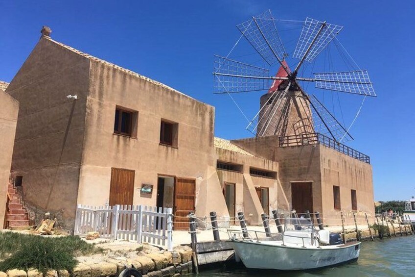 A windmill, a building, and a boat docked by the water. 3