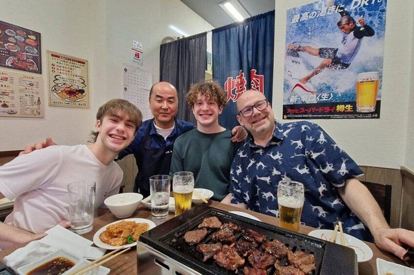 A group of people at a restaurant with a grill and drinks. 1