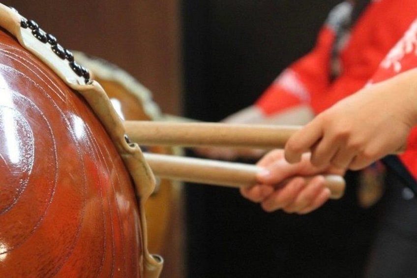 A person playing a large drum with two sticks. 4