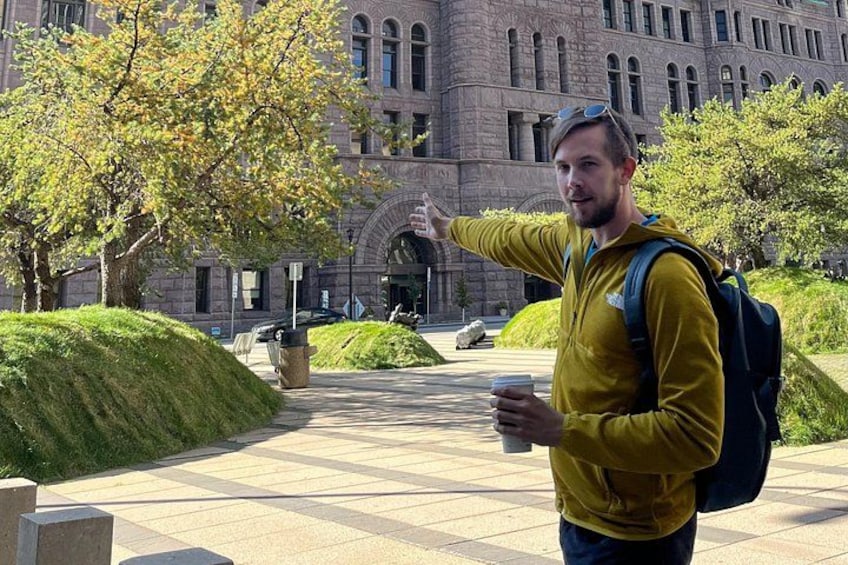 A person in a yellow jacket pointing towards a building with arched windows. 2