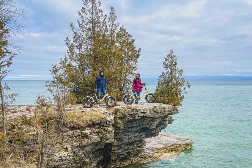 Two people on a rocky cliff by a lake. 1