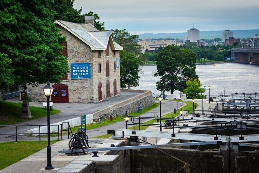 Un edificio de museo con un cartel, un río y un puente al fondo. 1