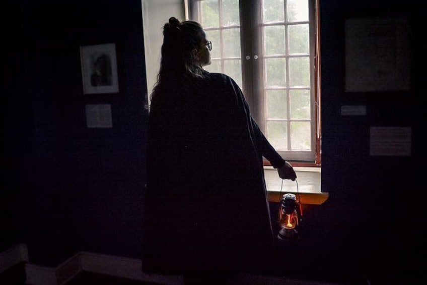 Una persona sosteniendo un farol en una habitación tenuemente iluminada con una ventana. 5