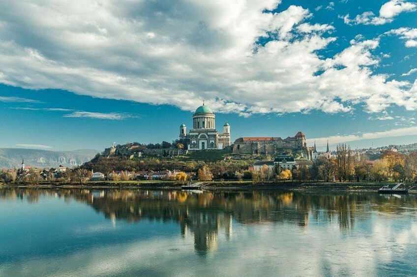 A historic building with a dome, a body of water in the foreground, and a cloudy sky. 2