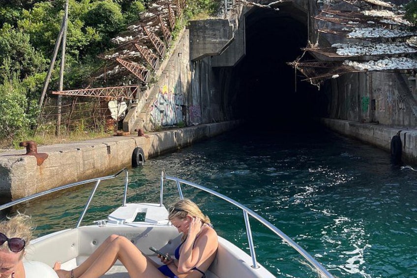 A boat navigating through a narrow waterway with a tunnel entrance and graffiti on the surrounding walls. 3