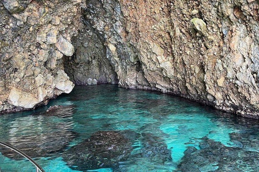 A natural cave with clear turquoise water and rocky walls. 5