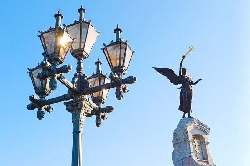 Una farola y una estatua de un ángel sosteniendo una cruz. 5