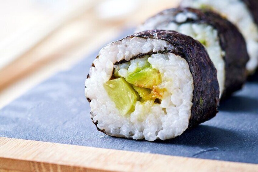 Sushi rolls with rice and avocado on a blue surface. 3