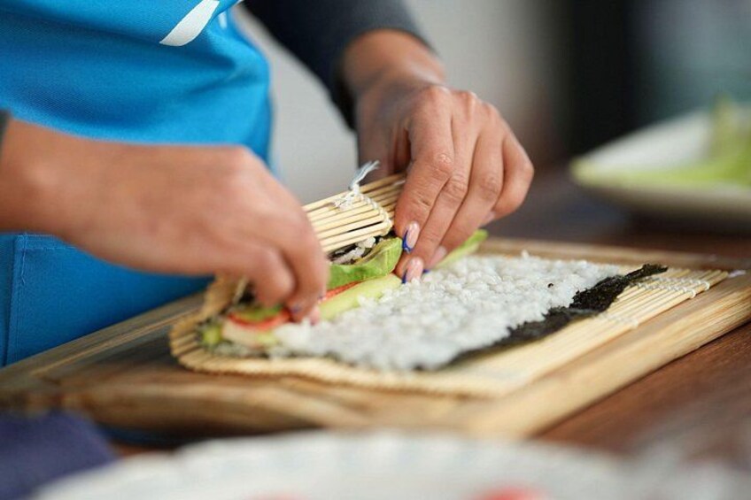 A person preparing sushi on a wooden board. 2