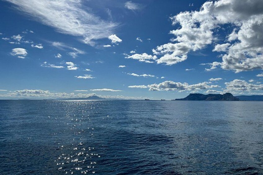 A calm sea with a clear sky and distant landforms. 1