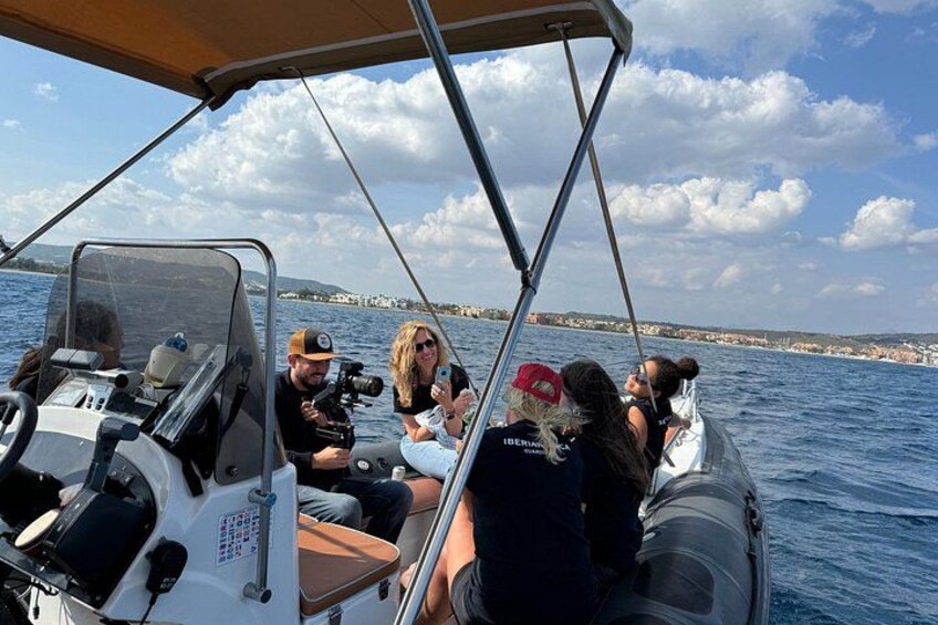 A boat with people on board, a clear sky, and a coastline in the background. 4