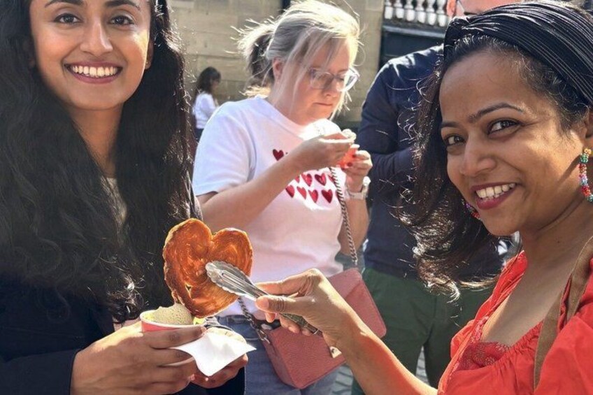 A person holding a heart-shaped pastry with a spoon. 5