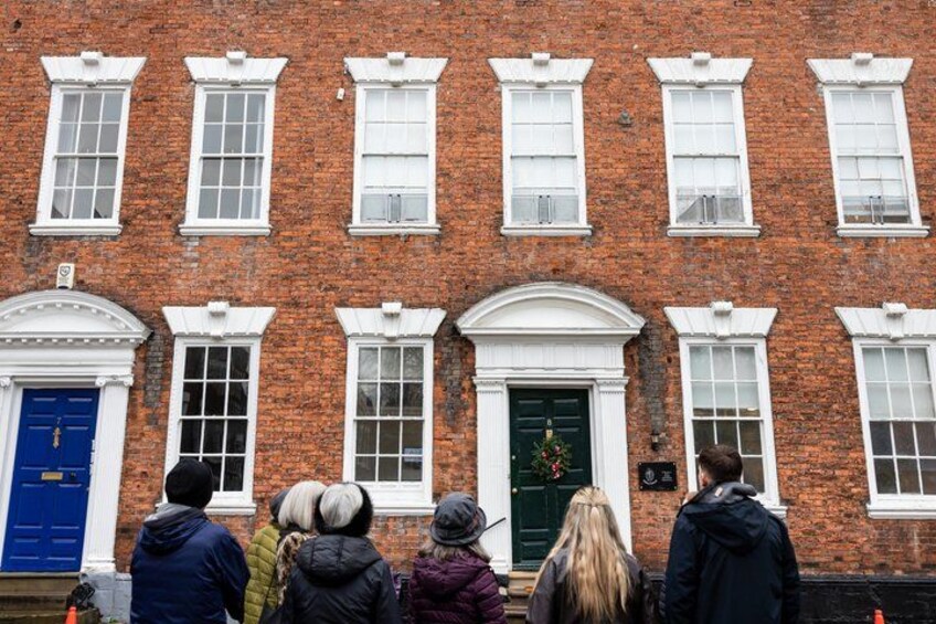 A red brick building with white windows and doors, a blue door, and a green door with a wreath. 2