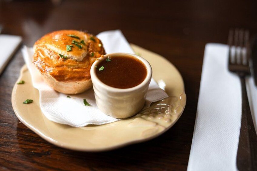 A plate with a pastry and a small bowl of sauce, placed on a wooden table. 3
