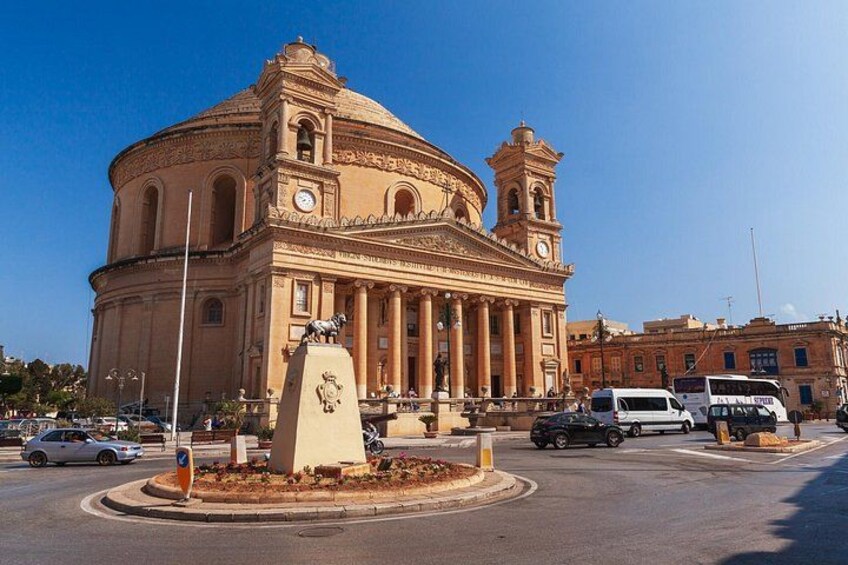 A historic building with a dome and bell tower, surrounded by a roundabout with vehicles. 4