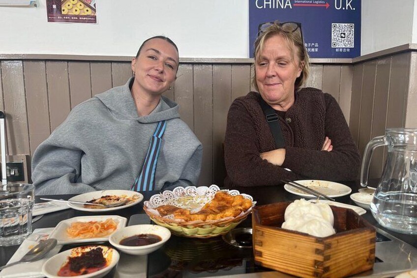 Two people sitting at a restaurant table with various dishes and a pitcher of water. 5
