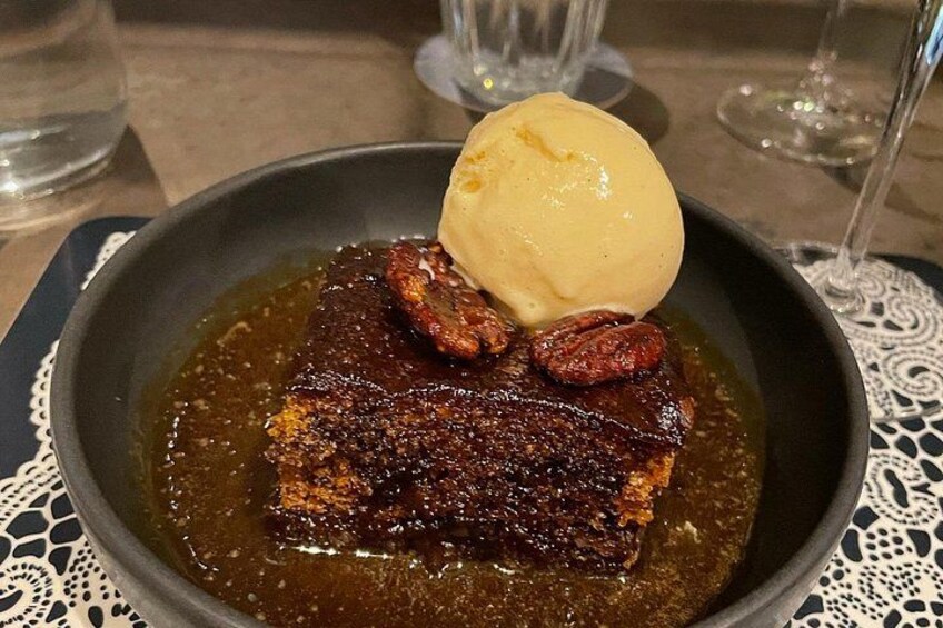 Un dessert avec une couche supérieure caramélisée, une boule de crème glacée et des noix de pécan, le tout présenté sur une assiette. 2