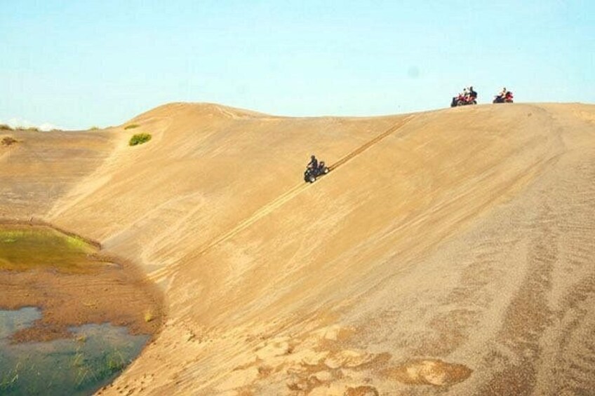 A sandy hill with a person riding a motorbike down the slope. 5