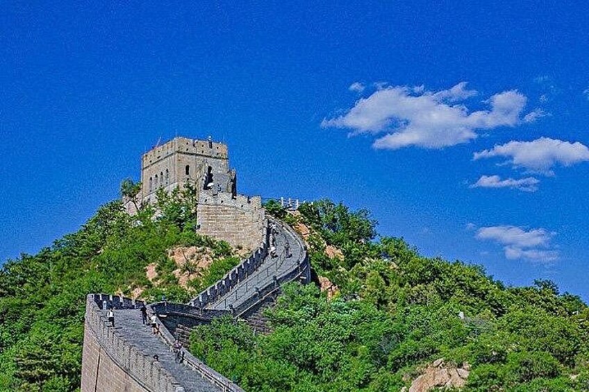 The Great Wall of China winding through lush green hills under a clear blue sky. 4