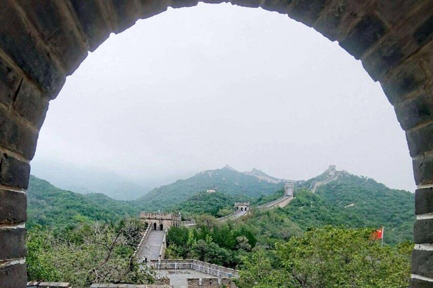 A stone archway overlooking a mountainous landscape with a pathway and traditional Chinese architecture. 5