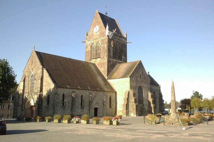 En historisk kirke med et klokketårn, buede vinduer og en statue foran. 4
