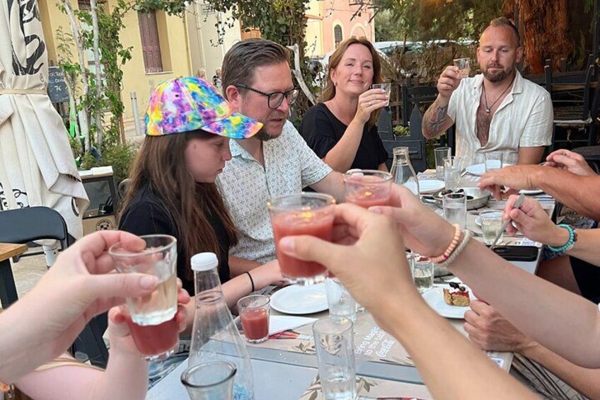 Een groep mensen die met drankjes proosten aan een buitentafel. 5