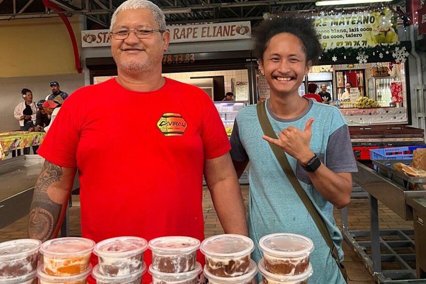 Two people standing in front of a food stall with various food containers. 5