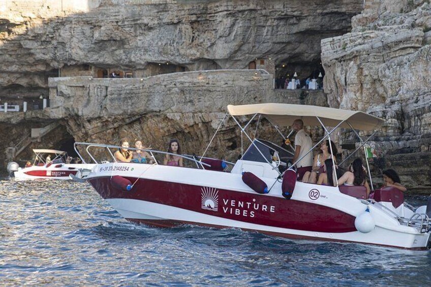 En båt med texten ”Venture Vibes” målad på sidan låg förtöjd nära branta klippor. 5