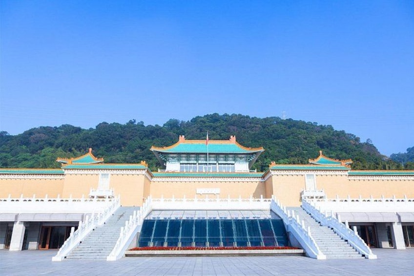 A traditional building with a green roof, white walls, and a staircase leading to a blue glass entrance. 5