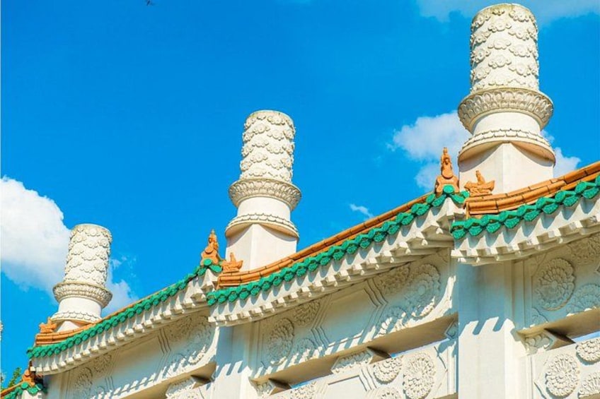 A building with ornate white and green roof tiles, detailed carvings, and a clear blue sky. 1