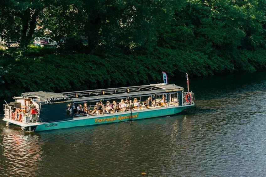 Un barco de paseo fluvial con pasajeros, rodeado de abundante vegetación. 4