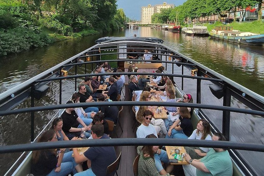 Un bote con gente cenando y un río con edificios al fondo. 3