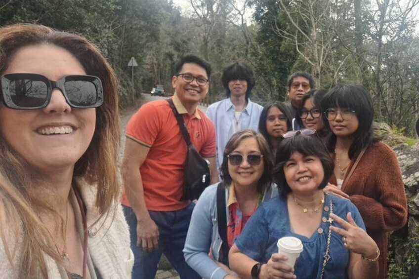 A group of people outdoors, possibly on a hike or nature walk, with trees and a road in the background. 4