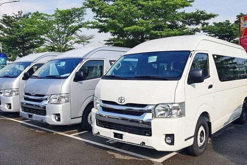 A row of white Toyota vans parked in a lot with trees in the background. 4