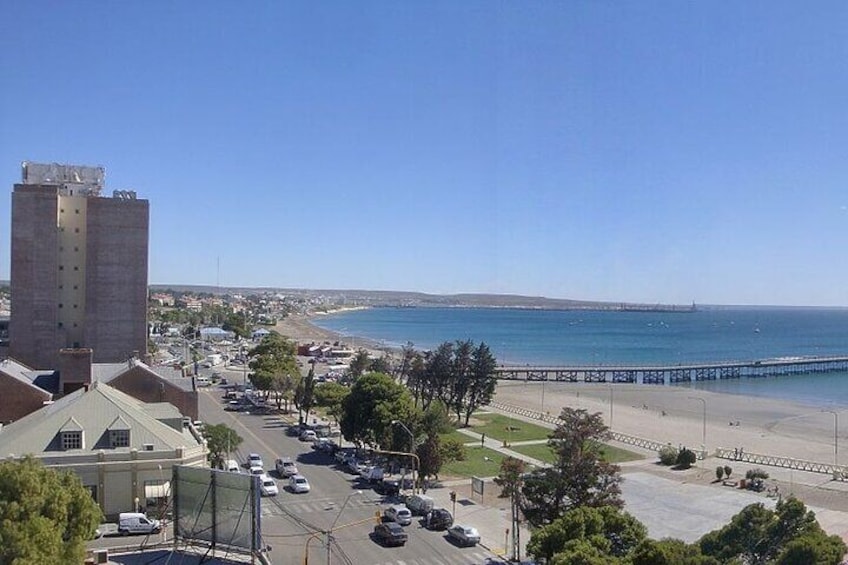 Un paisaje urbano costero con un edificio destacado, una playa y un muelle. 4