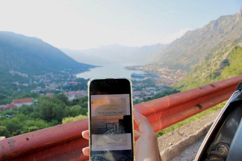 Un teléfono inteligente mostrando una vista panorámica de un paisaje montañoso con un río y un pueblo. 2